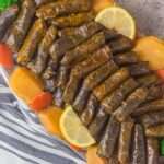 Grape leaves stuffed with rice and veggies with slices of potatoes and carrots