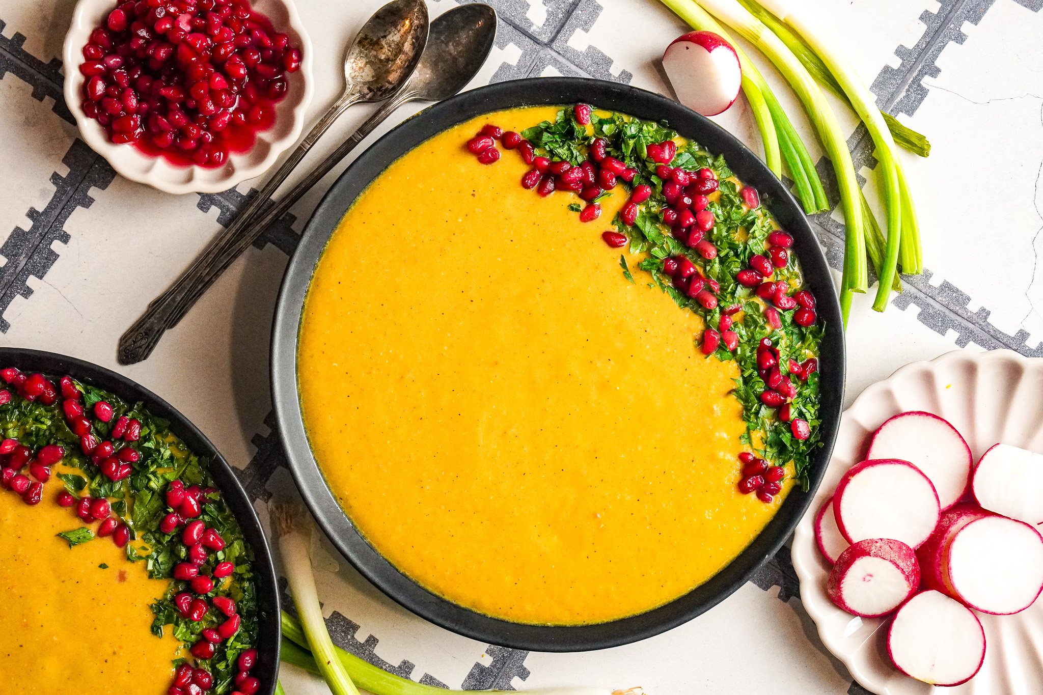 A delicious bowl of lentil soup topped with sprinkled with parsley, pomegranate and a slice of lemon.