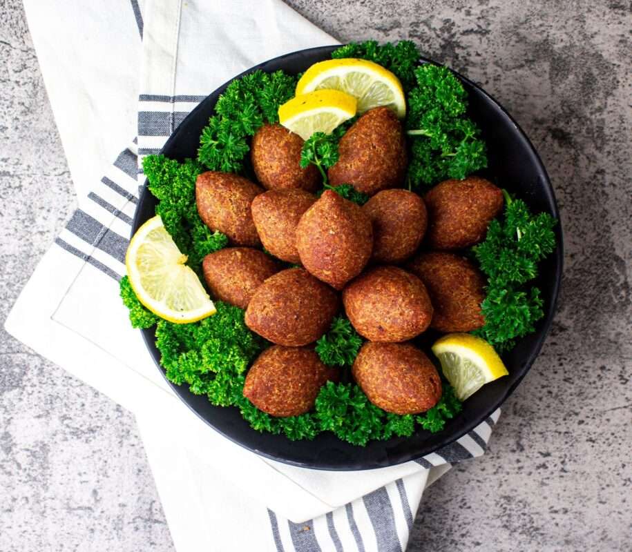 A platter filled with fried kibbeh balls with a crispy outer layer and a flavorful filling