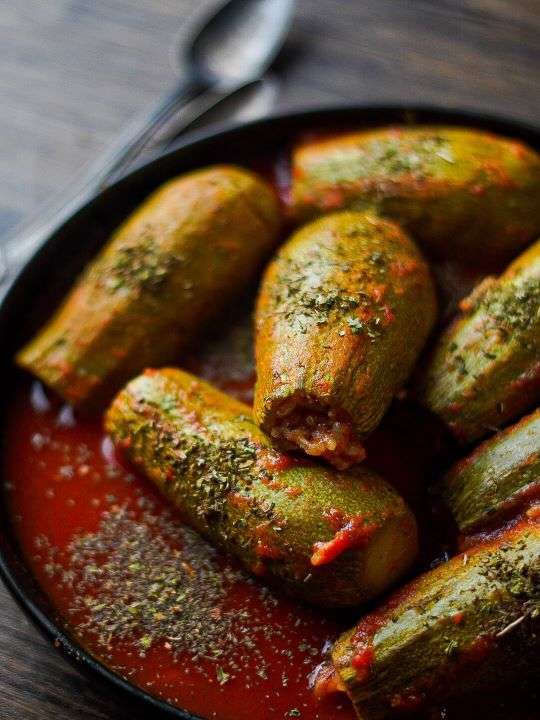 Brightly green tender zucchinis are sinking in a broth of tasty tomato sauce.