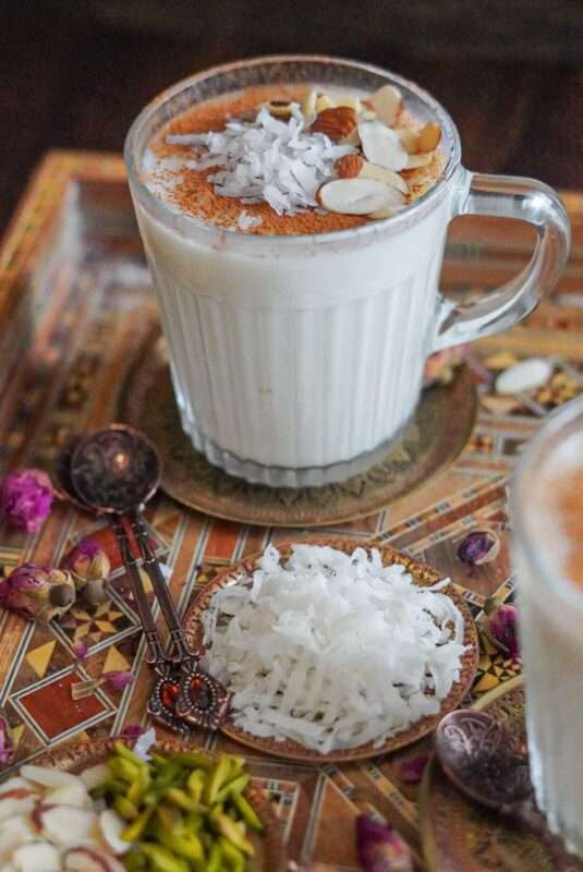 delicious homemade sahlab drink topped with ground cinnamon, almonds, and shredded coconut