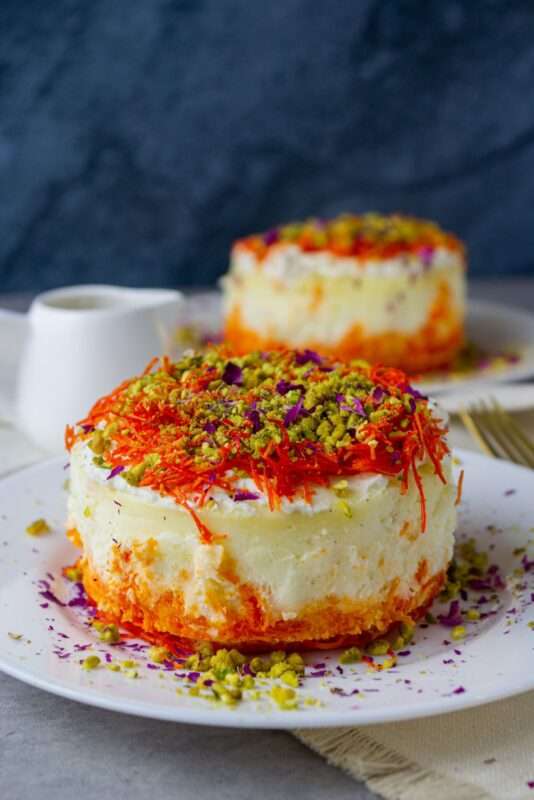 mini knafeh cheesecake topped with ricotta cheese and red-colored crunchy dough and garnished with chopped pistachios and rose petals