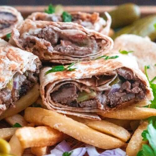A beef shawarma wrap served with French fries, pickles and sumac onions.