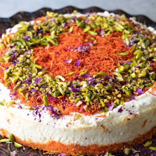 homemade refreshing knafeh cheesecake topped ricotta cheese and garnished with chopped pistachios and rose petals