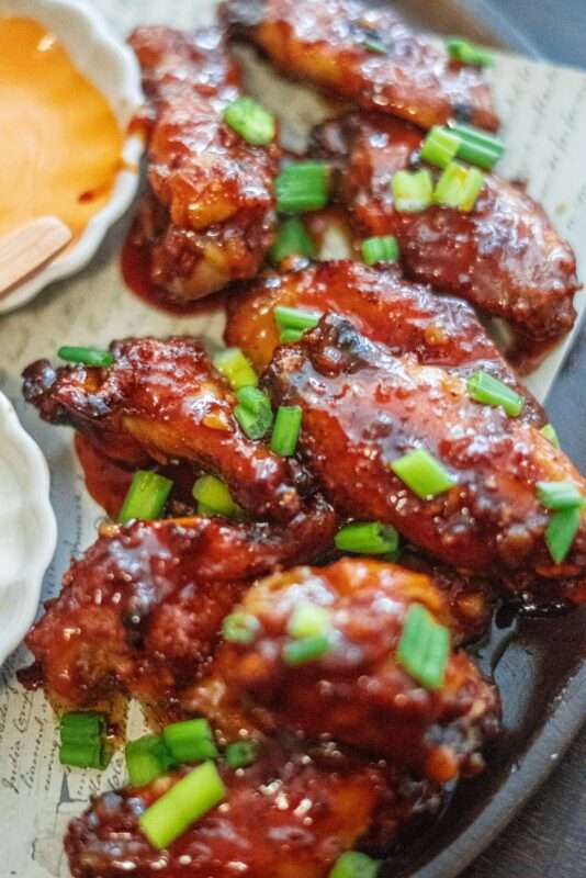Sriracha honey wings served on a plate sprinkled with fresh spring onions
