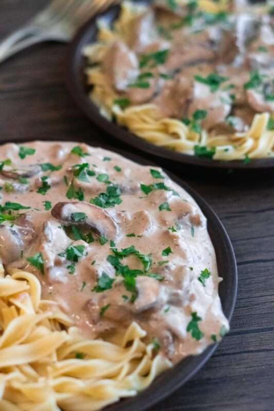 tender beef cooked with fresh mushrooms and tossed with the creamiest Stroganoff sauce. Served over a plate of noodles and garnished with fresh green parsley.