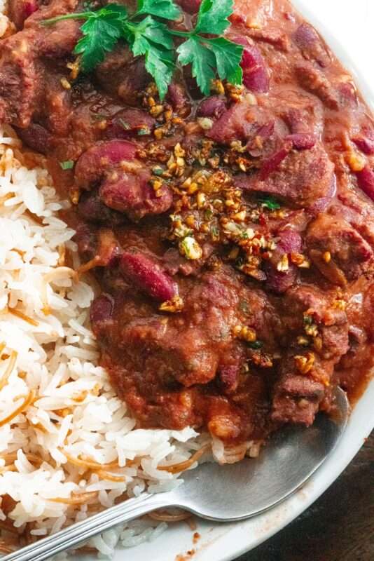 Delicious plate of Middle Eastern kidney bean stew layered with juicy tomato sauce, with vermicelli rice on the side, topped with parsley.