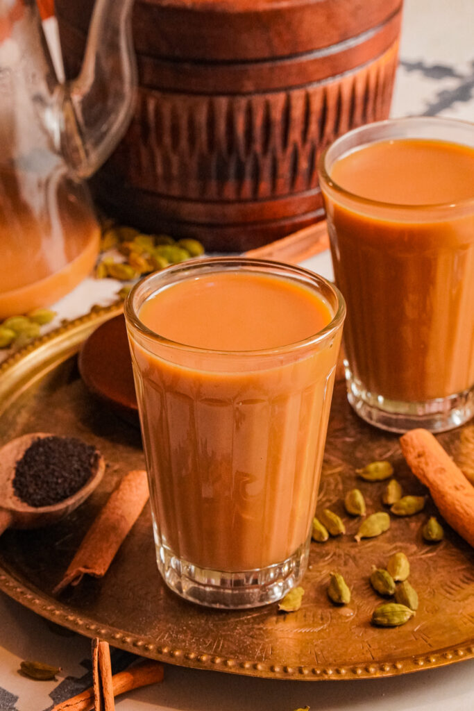 Hot cups of chai tea on a table with cardamom and cinnamon