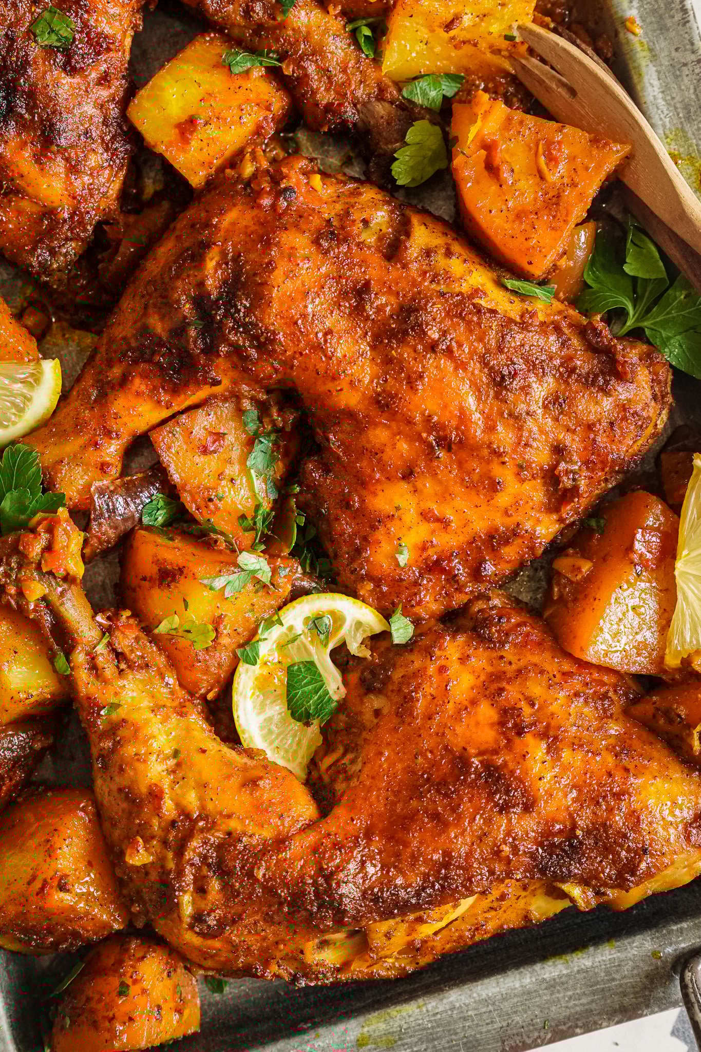 Baked golden leg quarters served in a plate with baked yellow potatoes. 