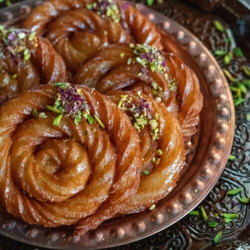 Mushabak Halabi , a super easy dessert made in spiral shapes and garnished with pistachios and dried rose petals.