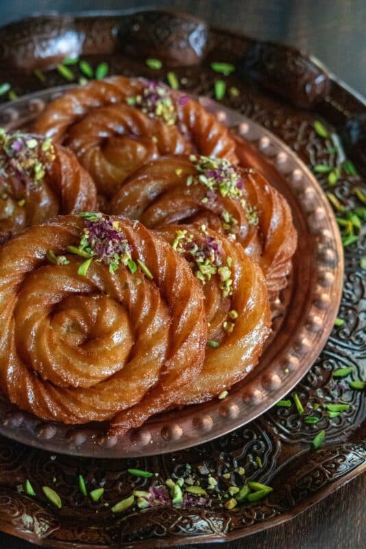Mushabak Halabi , a super easy dessert made in spiral shapes and garnished with pistachios and dried rose petals.