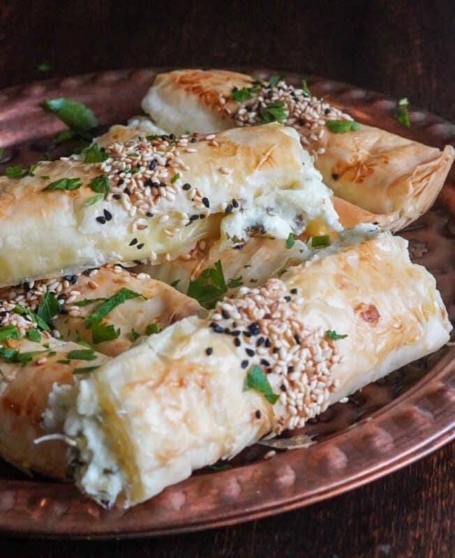 Appetizing grilled cheese borek with crispy texture, filled with cheese and parsley, topped with sesame and Nigella seeds. 