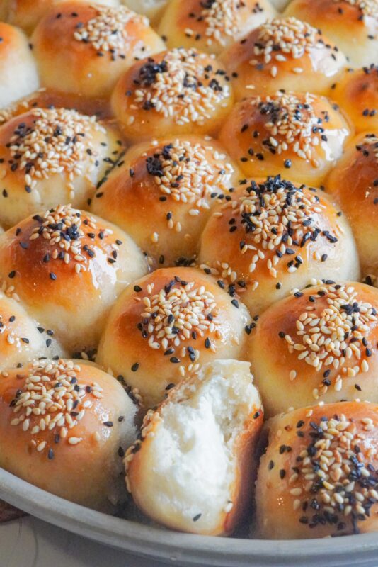 soft and fluffy bread rolls stuffed with cream cheese, topped with sesame seeds and Nigella seeds, and drizzled with divine honey 