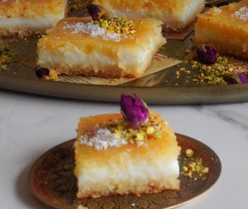 To enhance its visual appeal, basbousa bil qishta is garnished with pistachios, shredded coconuts and a rose