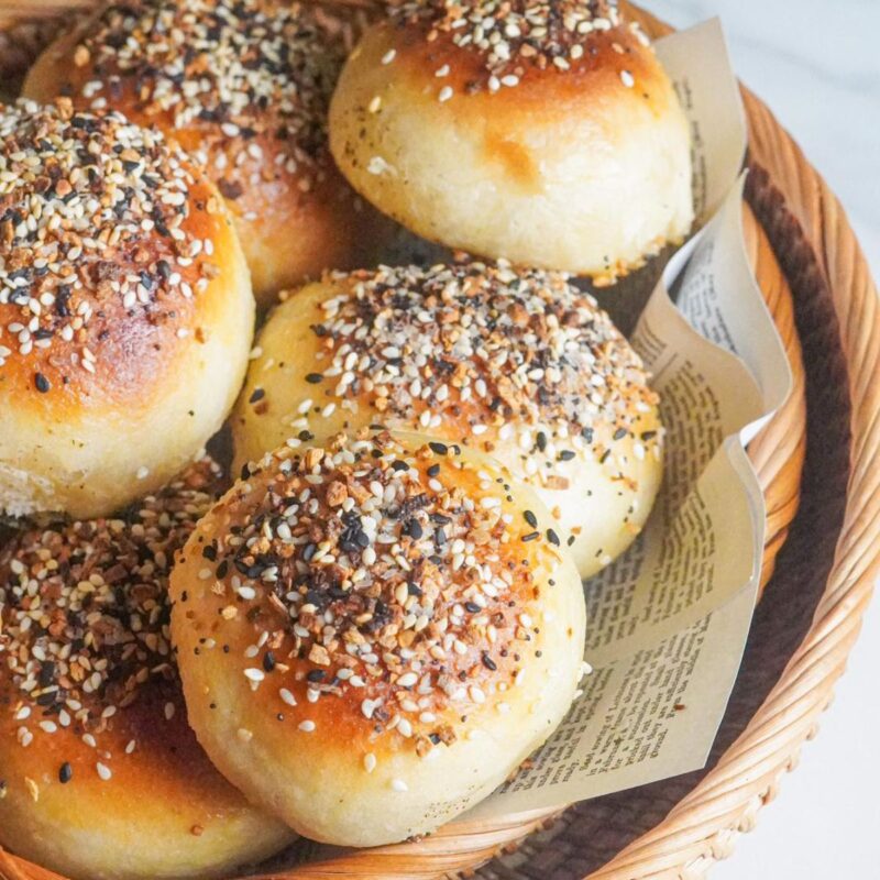 Perfectly baked bagel bites inside a basket sprinkled with sesame and poppy seeds