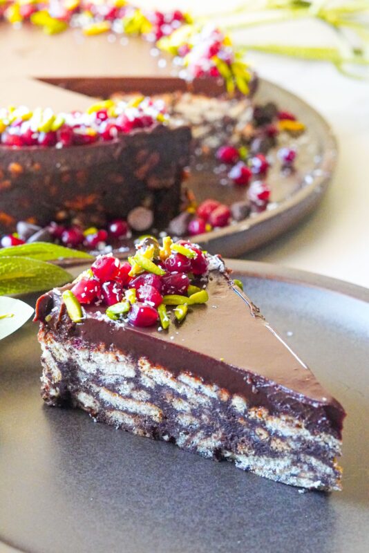 A piece of a soft and chocolaty lazy cake and on top we have pomegranate seeds, shredded coconut and crushed pistachios.