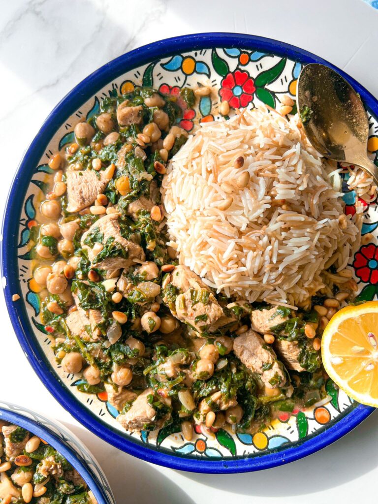 a healthful spinach stew and rice dish served with half lemon