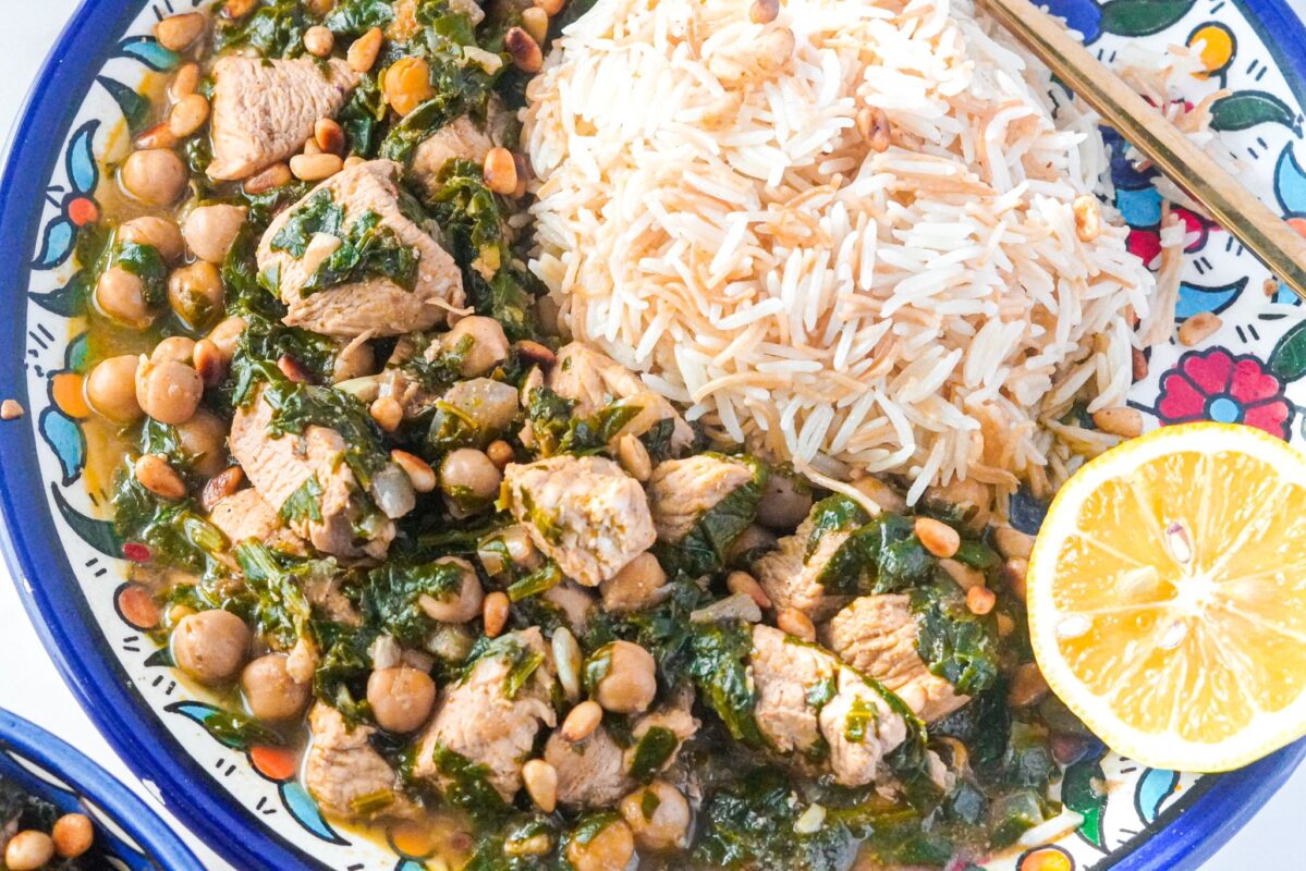 easy spinach stew served with vermicelli rice, topped with chicken, pine nuts, and lemon