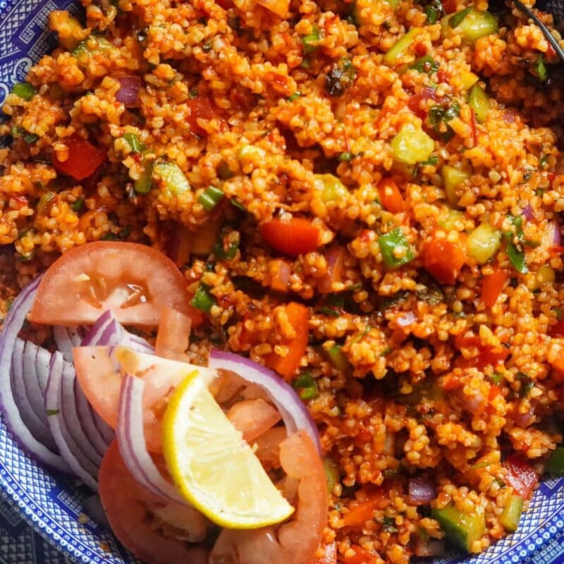 bulgur grains mixed with tomatoes, cucumbers, mint, parsley, green onions, and other ingredients form the famous Kisir salad served with red onion wedges, tomato slices, and lemon wedge