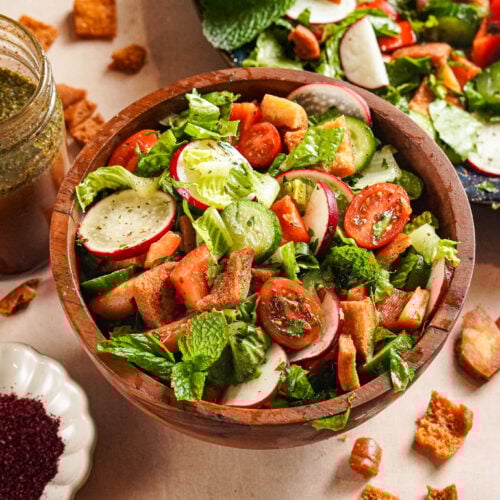 Vibrant green Fattoush served in a white and blue bowl topped with pita chips