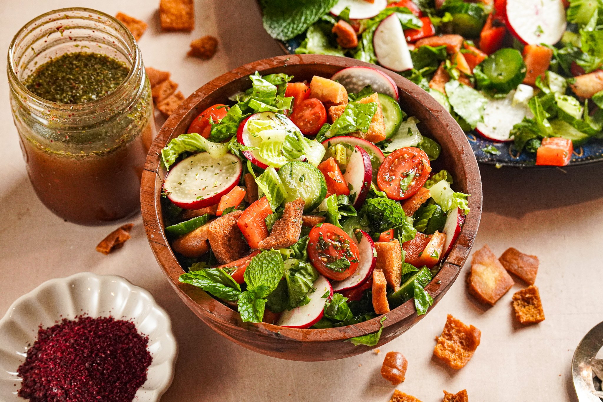 Vibrant green Fattoush served in a white and blue bowl topped with pita chips