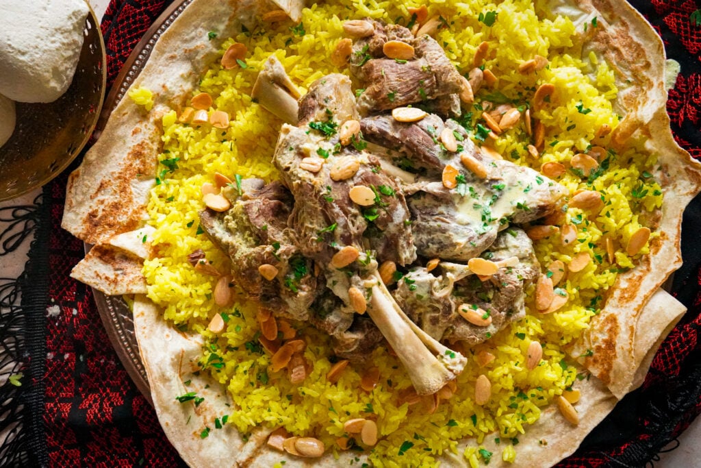A dish of authentic mansaf that consists of fluffy rice, bread and topped with nuts. 