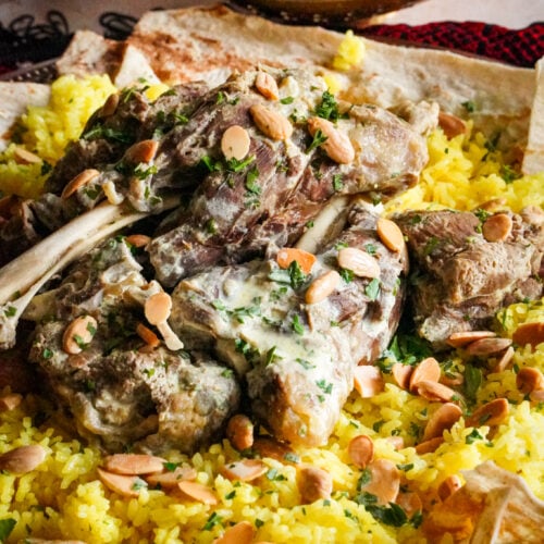 Mansaf is a delicious Jordanian dish with distinct flavors that includes bread, rice, meat, and a rich and tangy yogurt sauce. 