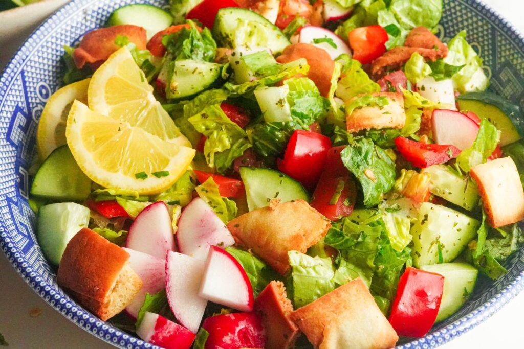 A bowl of colorful fattoush salad, featuring chopped veggies with lemon slices