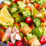A bowl of colorful fattoush salad, featuring chopped veggies with lemon slices