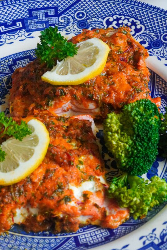 a quick nutritious baked salmon dish served with slices of lemon, broccoli, and herbs