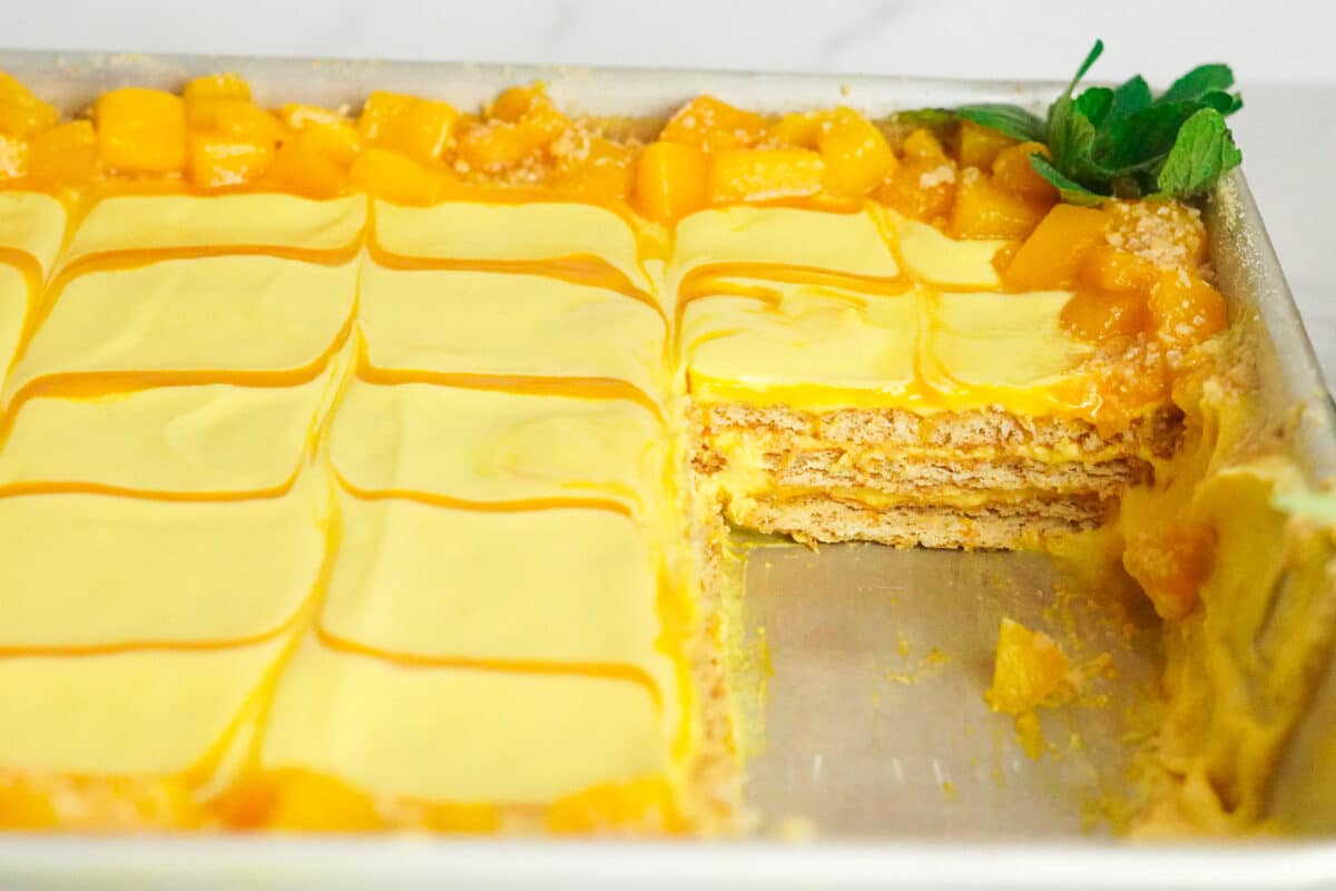 a tray of no bake mango cheesecake with diced mango on top