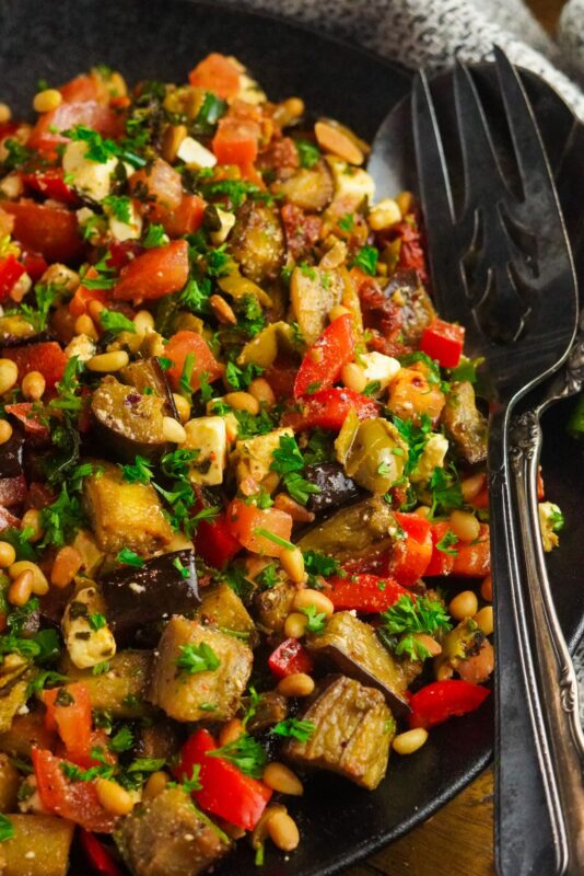 roasted eggplant salad in a bowl made with roasted eggplants, parsley, olives, tomatoes, green onions, and green bell pepper and seasoned with a savory dressing