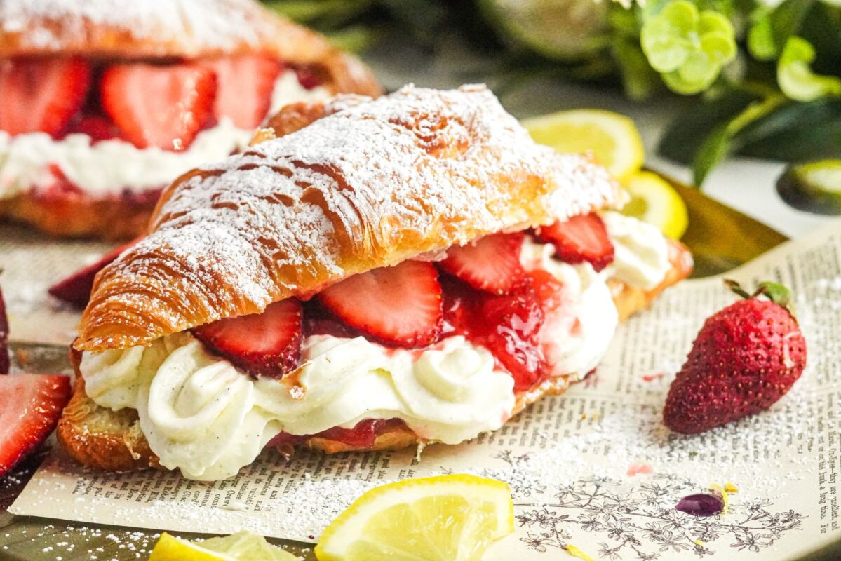 A croissant filled with strawberry cheesecake and fresh strawberry chunks, dusted with powdered sugar