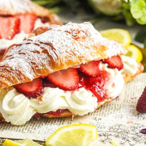 A croissant filled with strawberry cheesecake and fresh strawberry chunks, dusted with powdered sugar