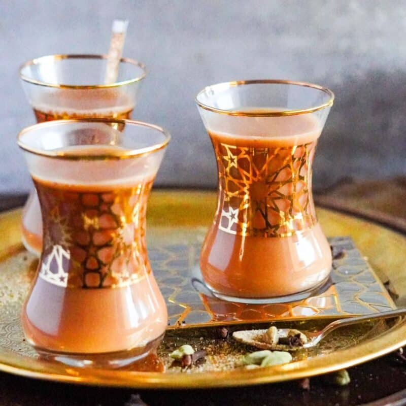 Three small glasses rest on a tray. The glasses are filled with Yemeni Tea.