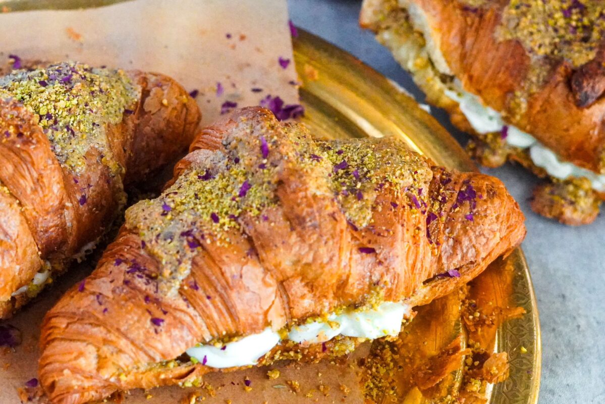 A large croissant stuffed with pistachio baklava paste and ashta and topped with a sprinkle of ground pistachios