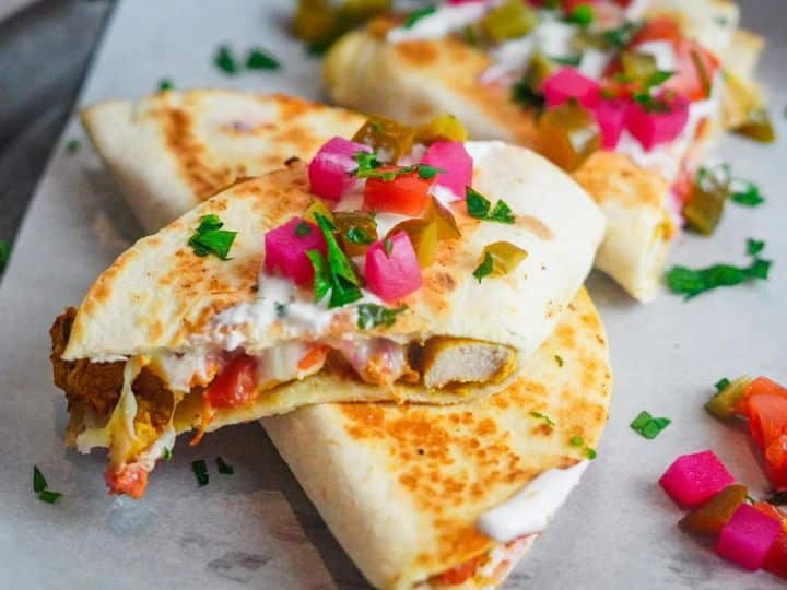 Two whole tortillas and one cut in half are placed near each other. They form the shawarma quesadilla recipe.