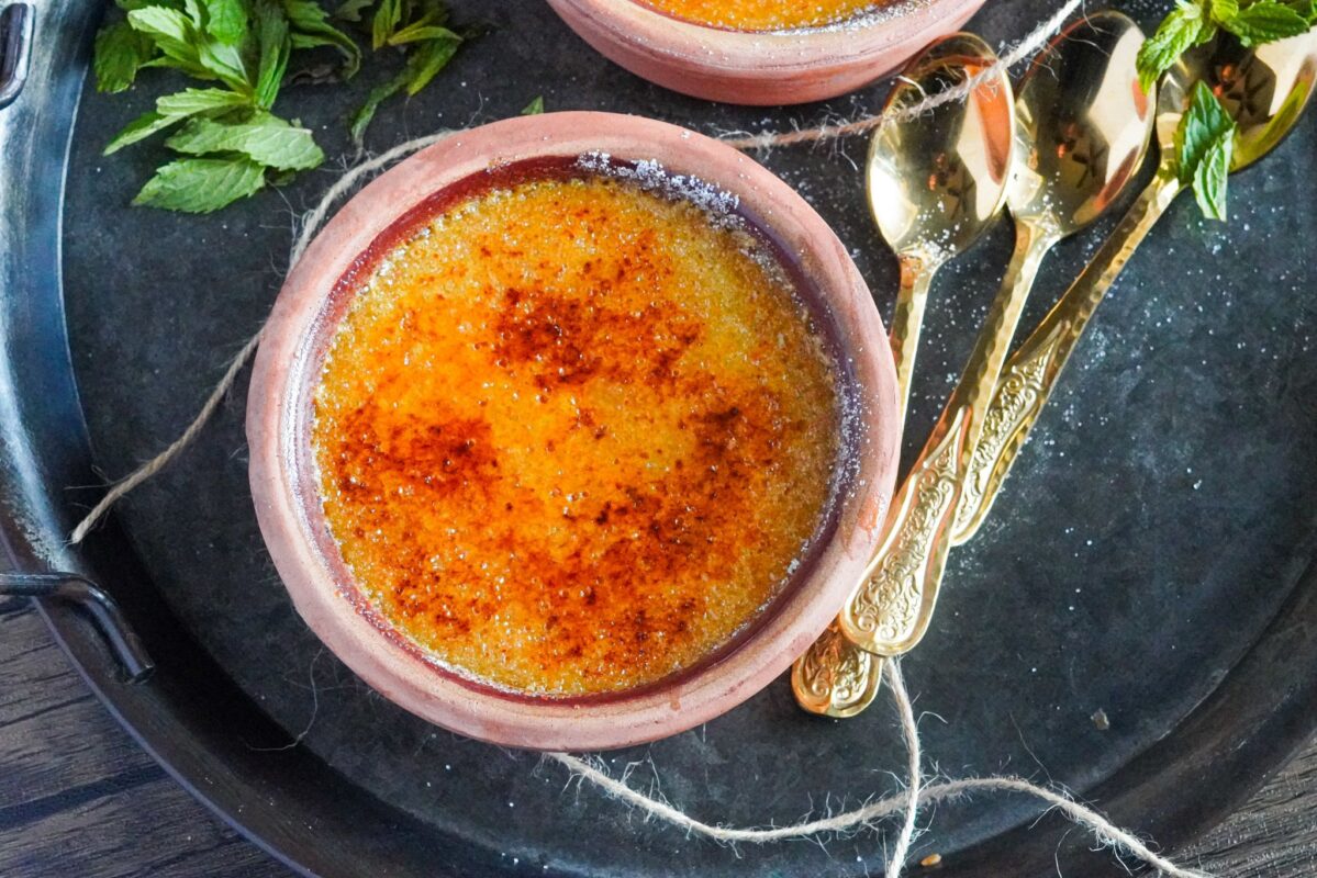Pumpkin spice creme brulé in a bowl on a tray with a few spoons next to it