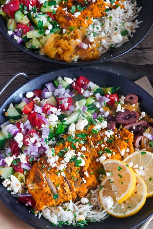 These Greek chicken rice bowls combine fresh vegetables and marinated and cooked chicken breast with fresh tomatoes, bell pepper, cucumber, Kalamata olives, lemon, and Feta served with Tzatziki sauce.