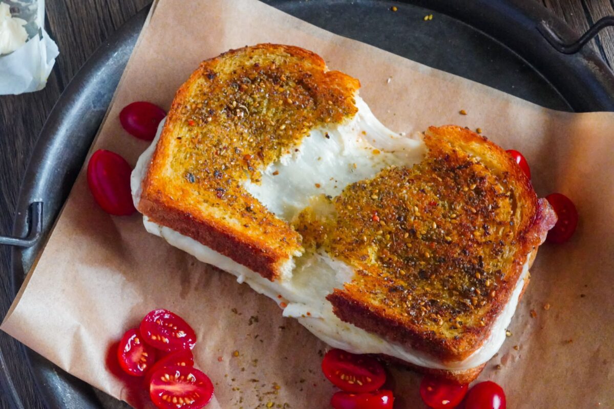 Stretching akawi and mozzarella cheese in a toast sandwich topped with zaatar