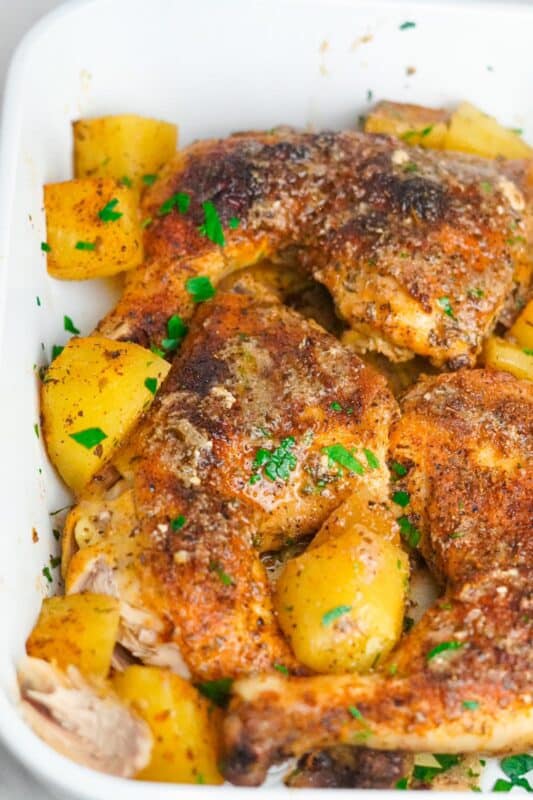 A pan of Greek-style chicken with potatoes baked to perfection garnished with finely chopped fresh parsley