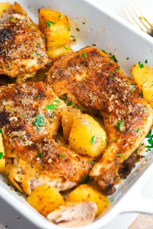 a pan of crispy chicken and potatoes garnished with chopped parsley