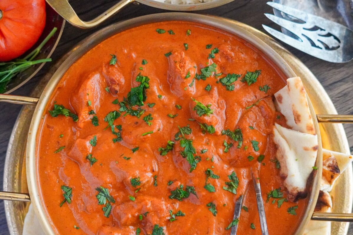 chicken tikka masala dish with marinated chicken pieces, rich in Indian flavor. It is garnished with finely chopped parsley.