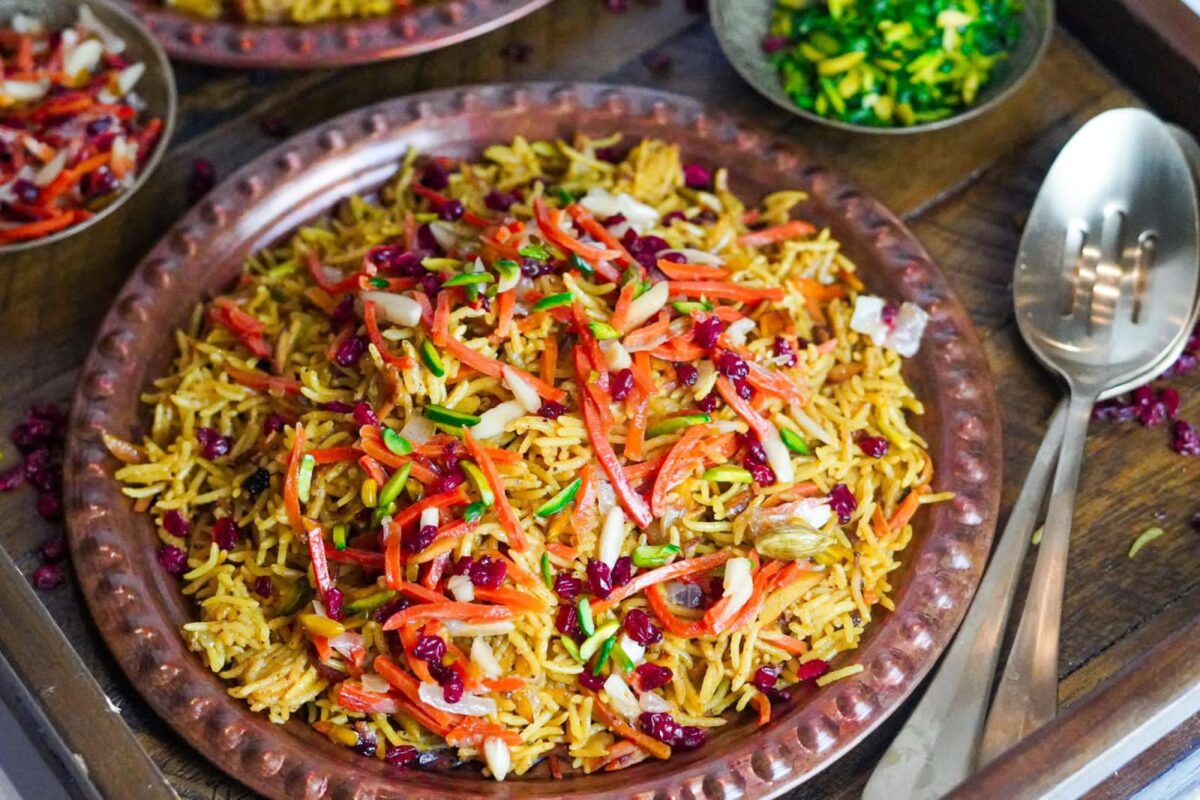 Colorful dish of jeweled Persian rice with the best toppings mix of shredded carrots, chopped pistachios, slivered almonds, and dried cranberries