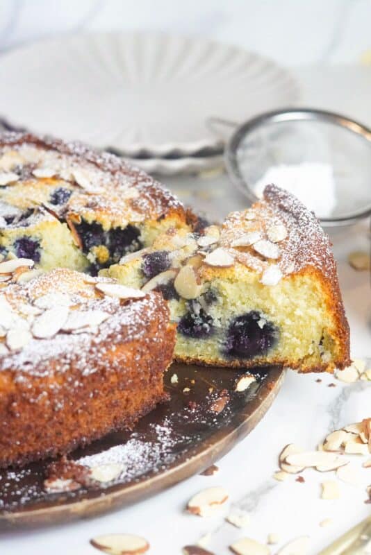 This delectable portion showcases a moist, creamy crumb structure enriched with the goodness of ricotta cheese and the sweetness of blueberries, complemented by the crunch of toasted almonds.