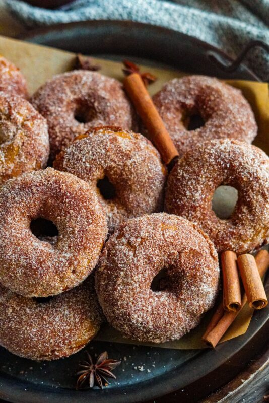 A pile of seasonal donuts paired with cinnamon sticks