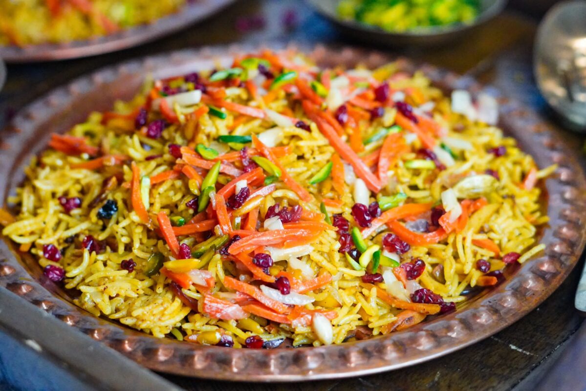 A rich dish of Iranian rice topped with pistachios and carrot shreds
