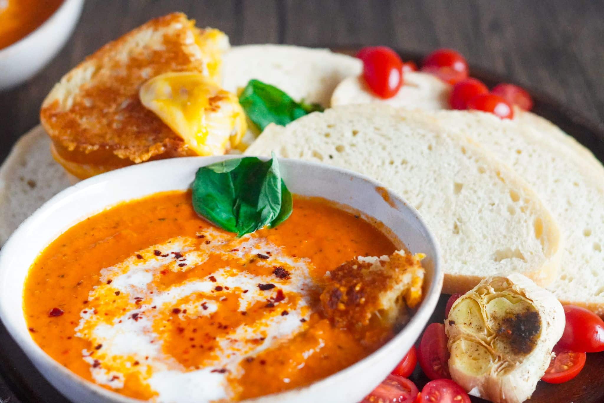a medium bowl of creamy cozy tomato soup served with bread slices