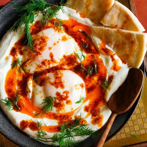 a plate of Turkish çilbir served with pita bread and sprinkled with a generous amount of chopped fresh dill