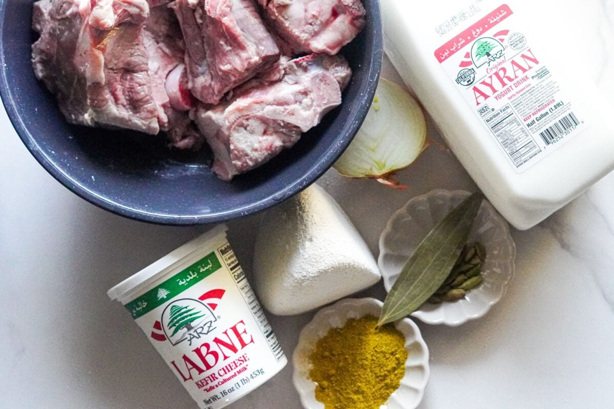 Some of the best and simple ingredients for Mansaf are placed on the table, which are: Lamb, Labneh, cumin, onion, and yogurt. 